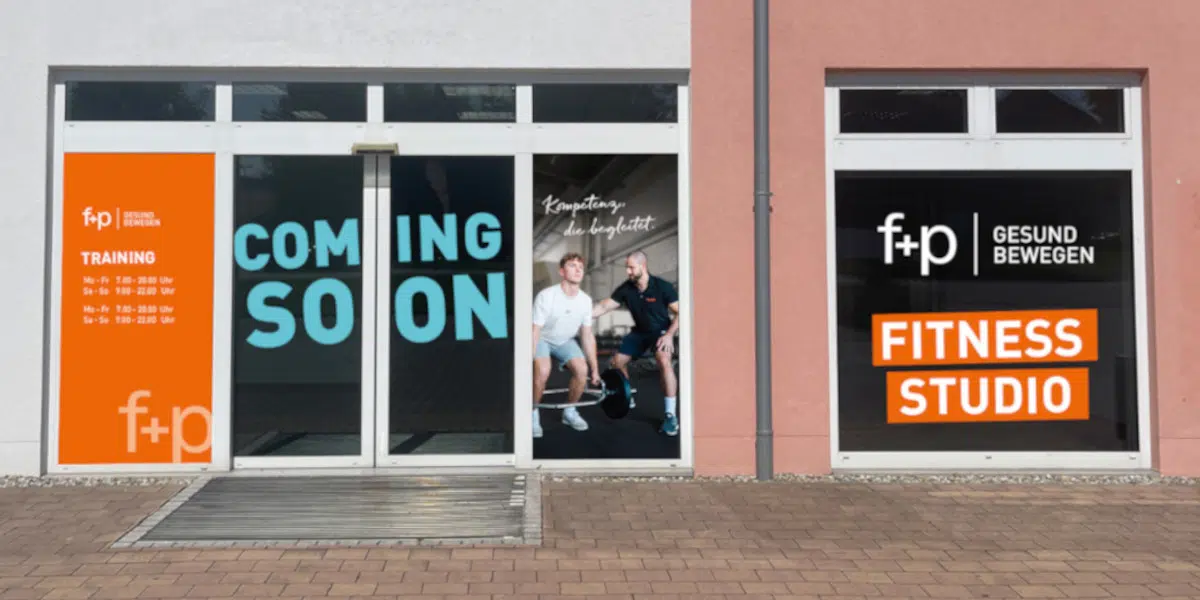 f+p Fitnessstudio, Coming Soon an der Fassade in Bad Grönenbach Die Fassade von f+p Fitness zeigt Türen mit „COMING SOON“ sowie ein orangefarbenes Schild „FITNESS STUDIO“.