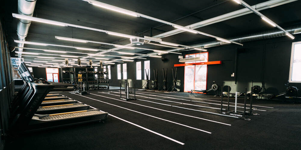 Fabrik Kempten, schwarze Trainingsfläche mit HYROX-Equipment und Laufbahnen Offene schwarze Trainingsfläche in der f+p Fabrik Kempten mit Laufbändern, markierten Bahnen, Rigs und HYROX-Equipment